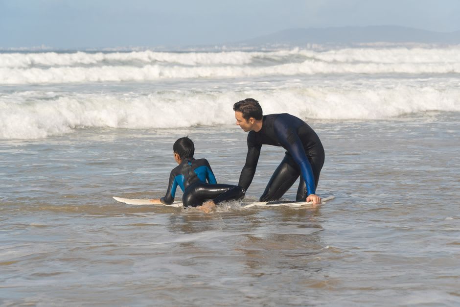 Surf instructor giving a lesson to beginners in the shallow water at Costa da Caparica
