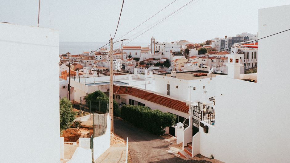 Faro old town limestone buildings glowing at golden hour, seen from within the walled Cidade Velha