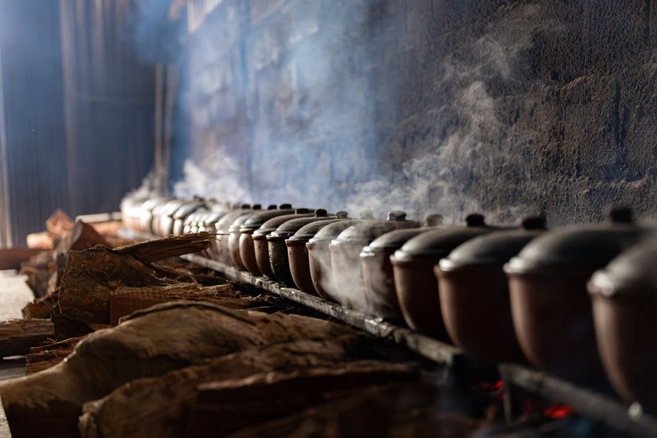 Cook lifting a steaming pot of cozido das Furnas out of a volcanically heated hole in the ground