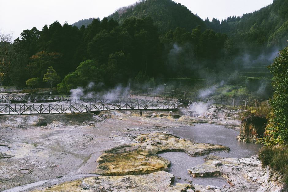 Steaming orange-tinted thermal pool surrounded by lush tropical garden at Terra Nostra Park in Furnas