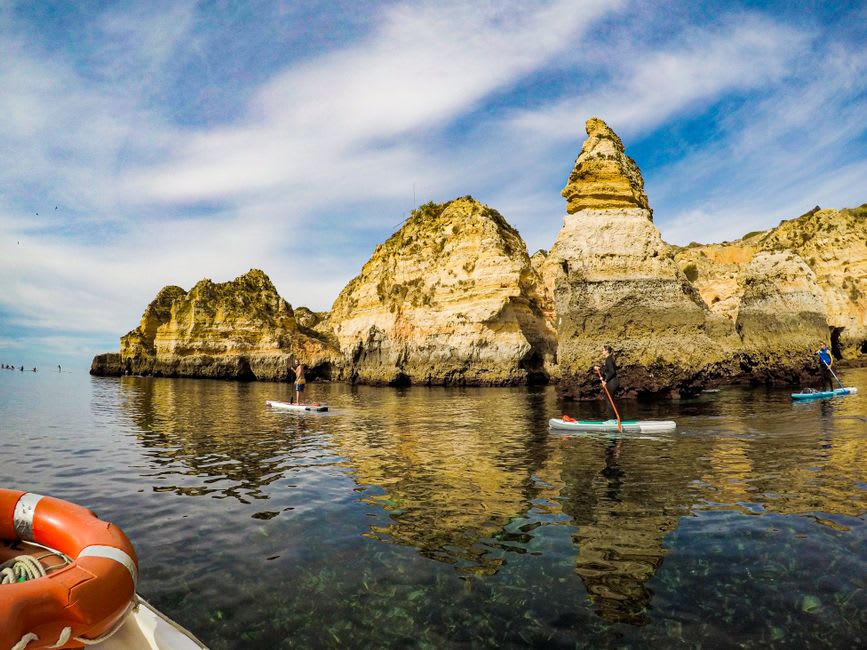Kayak gliding through a narrow sea cave at Ponta da Piedade with sunlight streaming through an opening in the rock