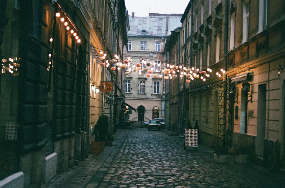 Lagos old town street at dusk with string lights strung between whitewashed buildings and bar tables filling the cobblestones