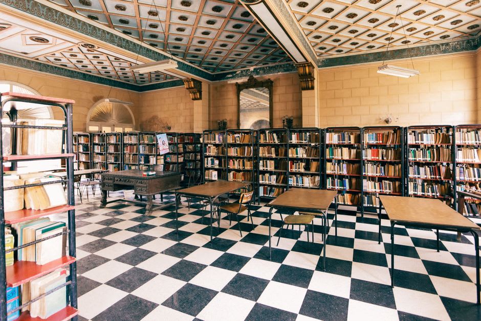 The vast Rococo library at Mafra Palace with ornate wooden shelving holding thousands of leather-bound books