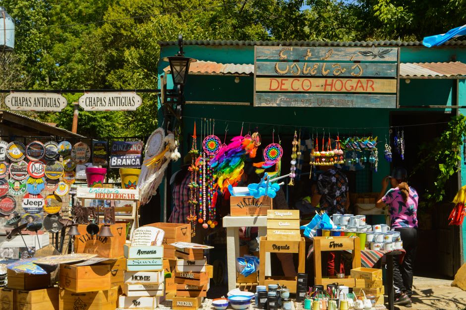 Roadside stall in the hills near Monchique selling homemade medronho brandy in unlabeled glass bottles alongside carved wooden crafts