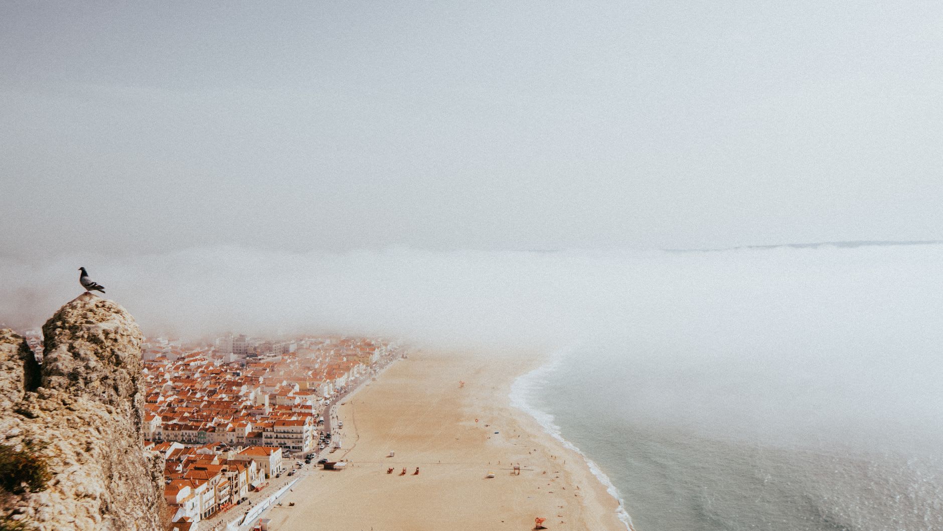 The red Nazaré lighthouse on its clifftop fort with surf exploding against the rocks below