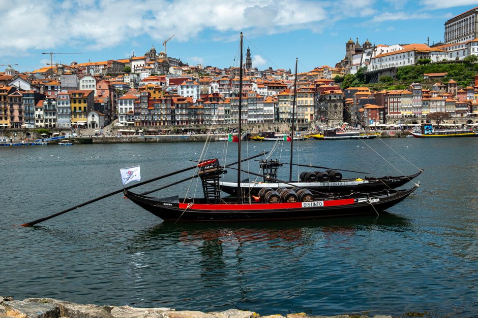 Traditional rabelo boat moored on the Douro river with vineyard terraces rising behind it