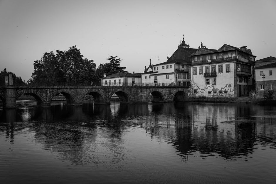 Roman-era stone bridge over the fast-moving Côa river near Sabugal with granite boulders in the water