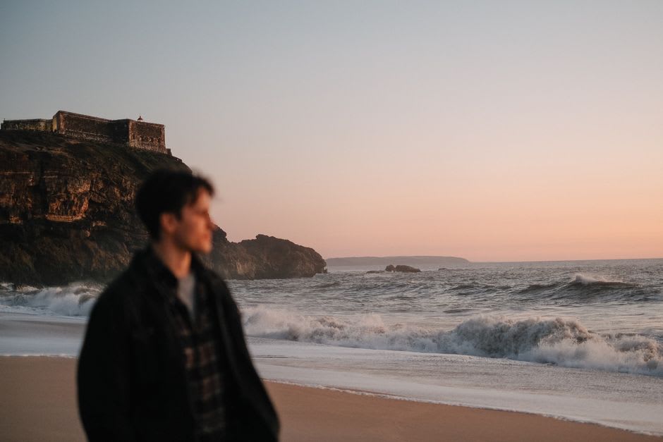 Sunset over the calm Mira river beach in Vila Nova de Milfontes with the fort silhouetted in the distance