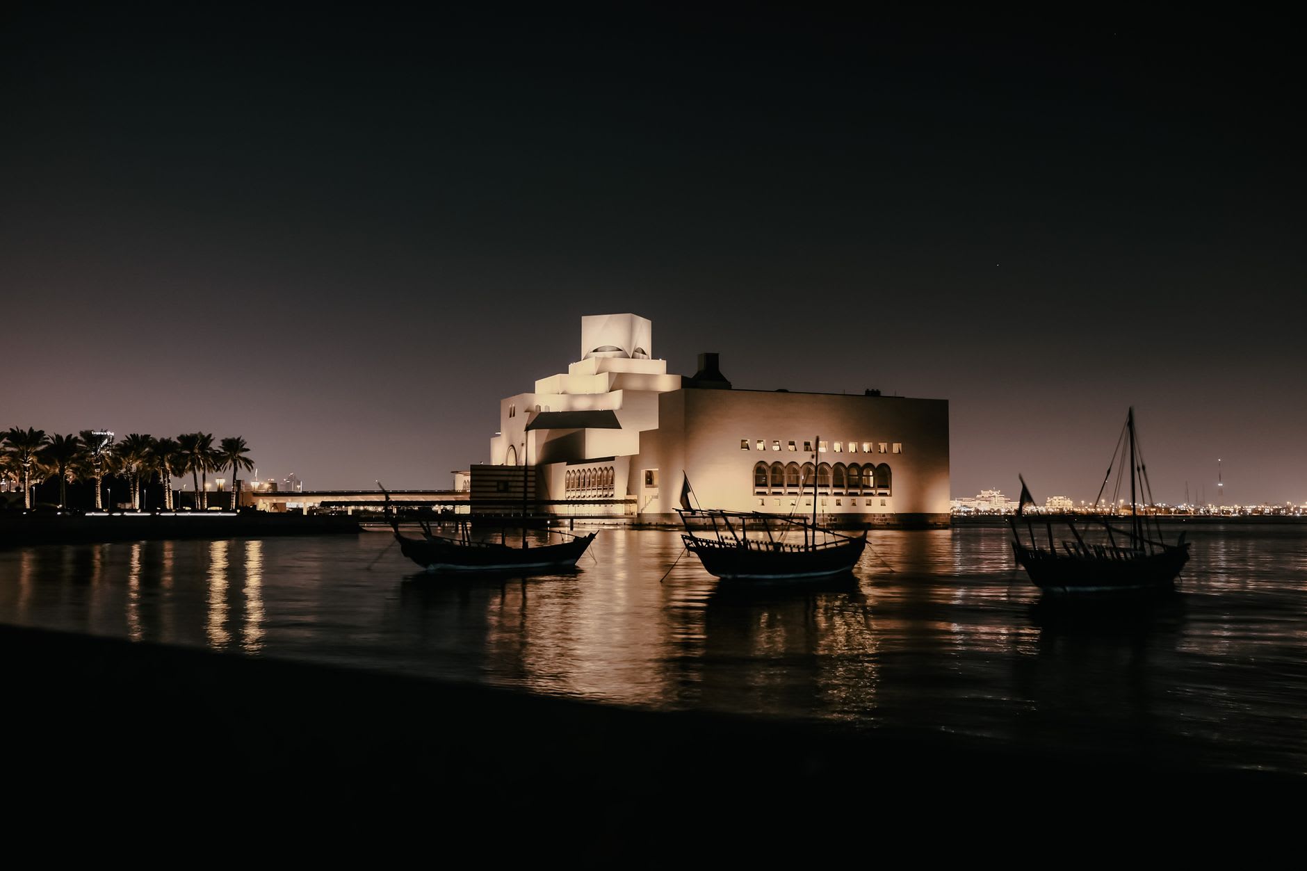 The Museum of Islamic Art causeway and entrance viewed from across the bay with Doha's skyline behind