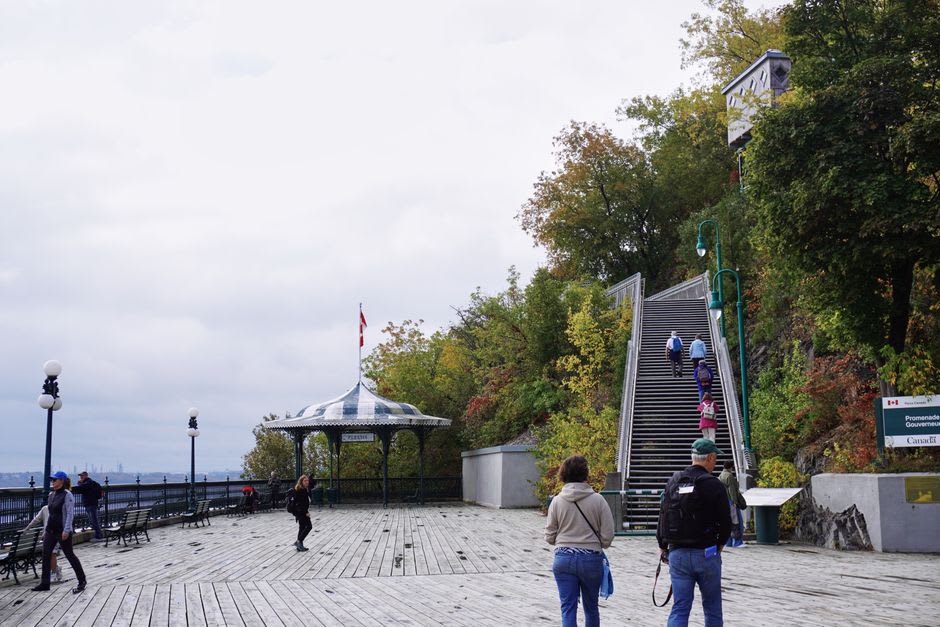 El paseo de madera de la Terrasse Dufferin extendiéndose a lo largo de lo alto del acantilado, con glorietas de techo verde y el río más allá