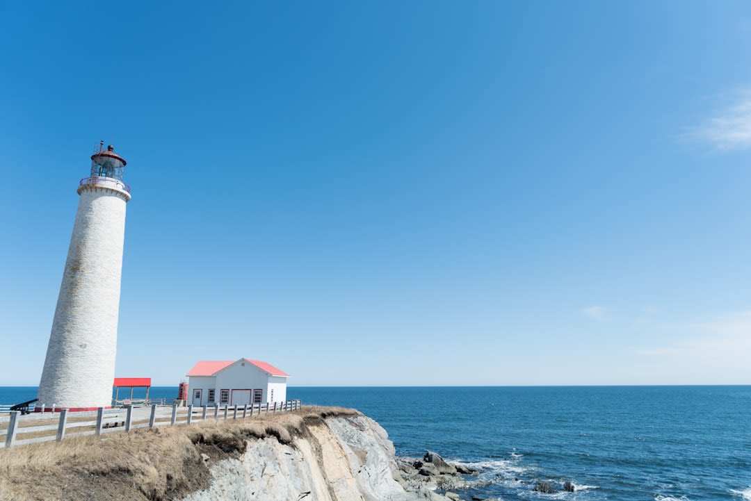 The Cap Gaspé lighthouse at the tip of Forillon National Park with dramatic sea cliffs and the Gulf of St. Lawrence stretching to the horizon