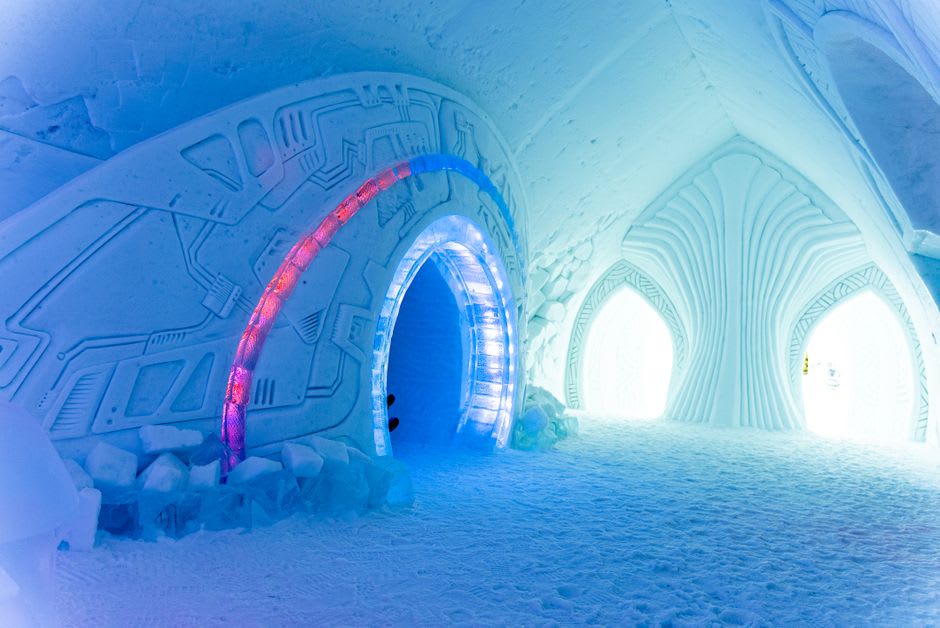 Carved ice bed frame draped in furs and thermal sleeping bags inside a themed suite at the Hôtel de Glace
