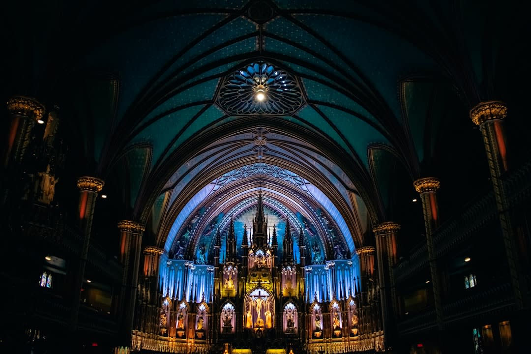 Luz solar a través de los vitrales de la basílica iluminando filas de bancos de madera en la nave