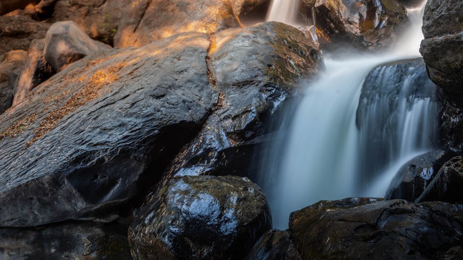 A close view of the columnar rock formations at Dorwin Falls with water cascading between the angular stone ledges