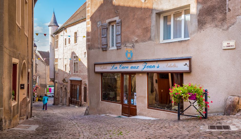La Rue Saint-Jean al anochecer con luz cálida saliendo de las ventanas de los restaurantes y peatones caminando por la calle estrecha
