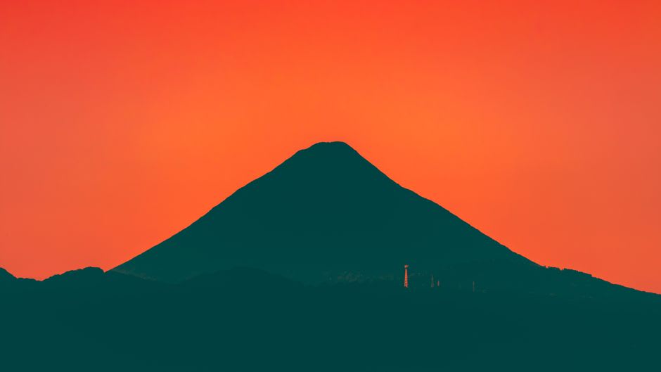 La silueta escarpada del monte Tibrogargan contra un cielo azul despejado, visto desde las tierras de cultivo circundantes