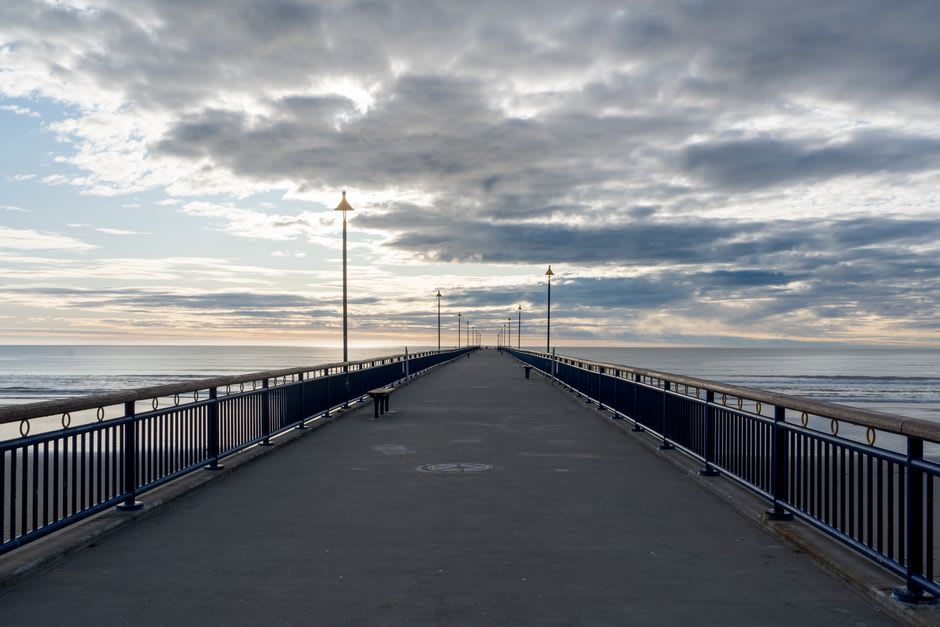 El muelle de Urangan extendiéndose hacia aguas tranquilas al atardecer, siluetas de pescadores a lo largo de su longitud