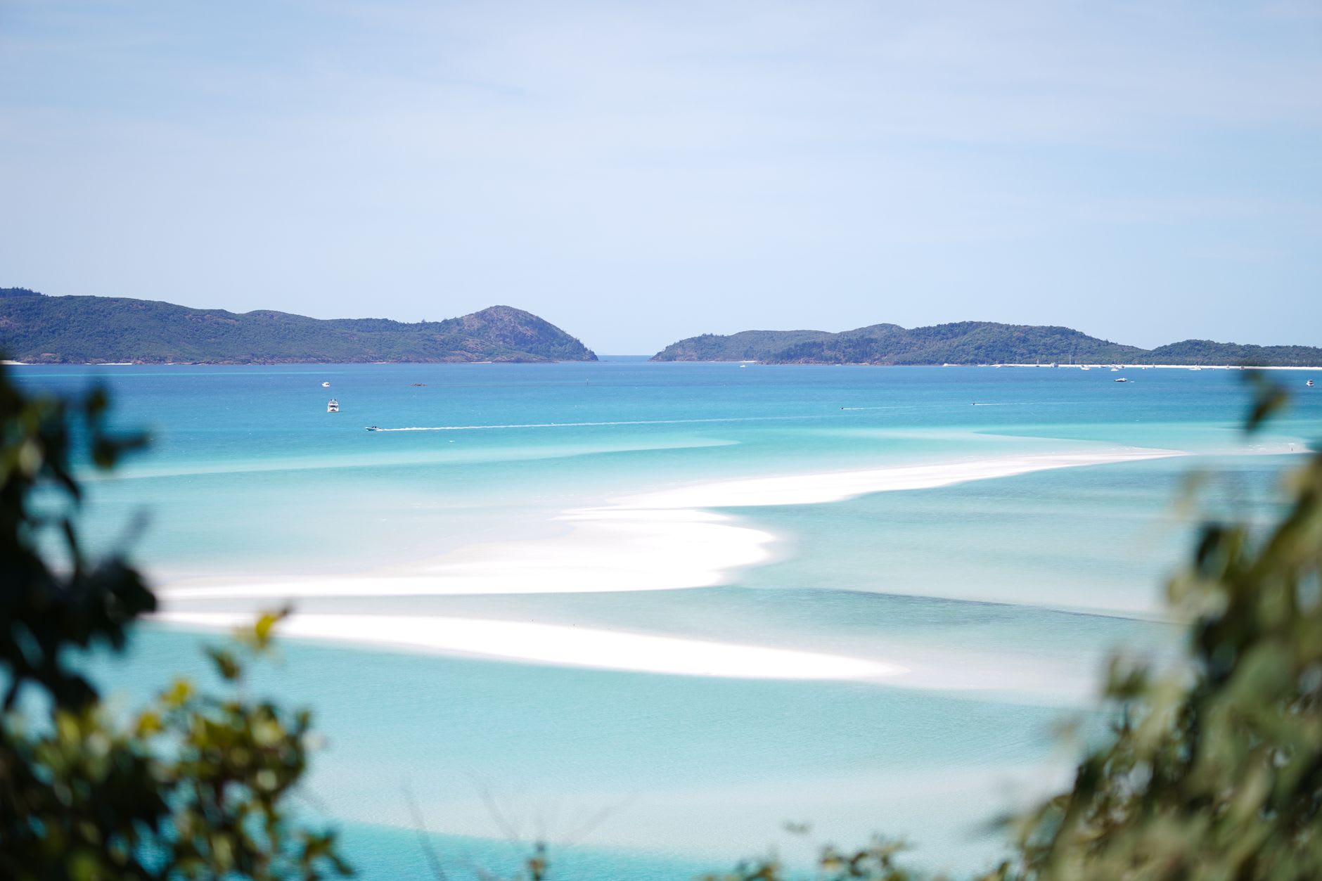 Catamaran anchored off Whitehaven Beach, turquoise water perfectly clear to the sand, late afternoon light