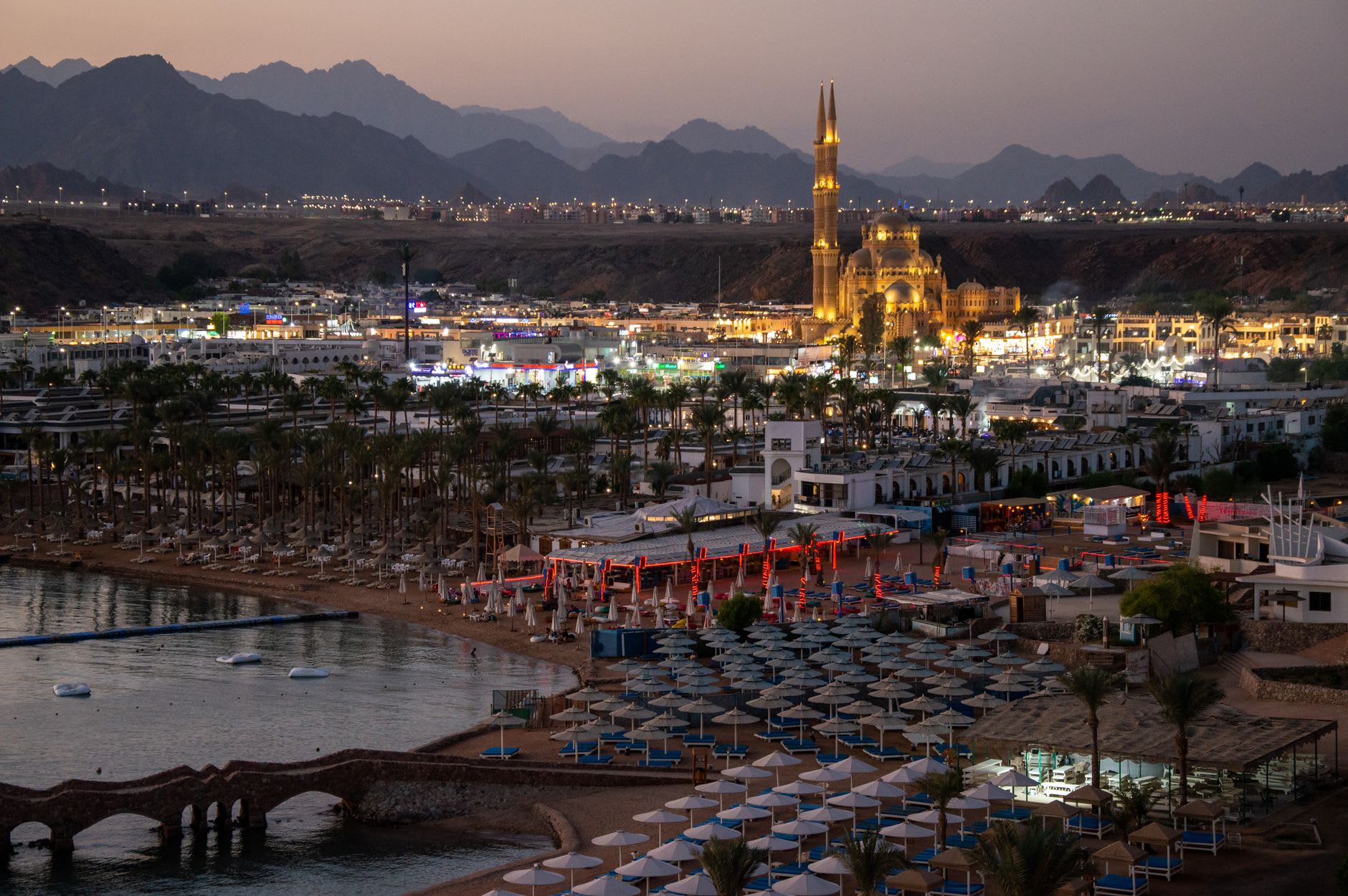 The harbor of El Quseir at dawn, wooden fishing boats moored along the waterfront with the Ottoman fort rising behind them