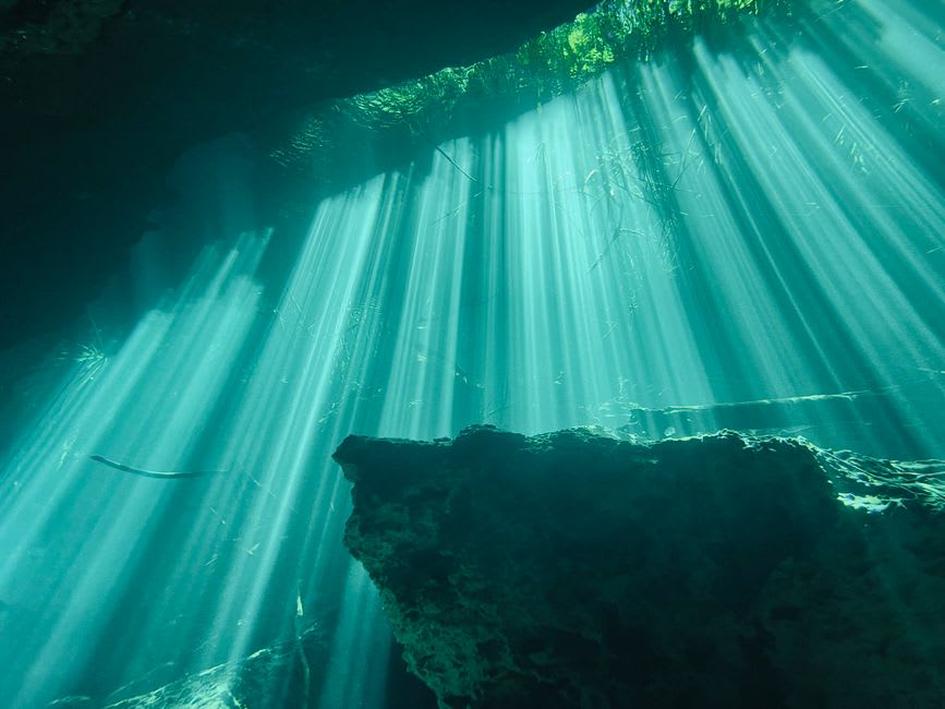 Sunlight streaming through an underwater cave opening at Abu Galawa Soraya within the Fury Shoals reef complex