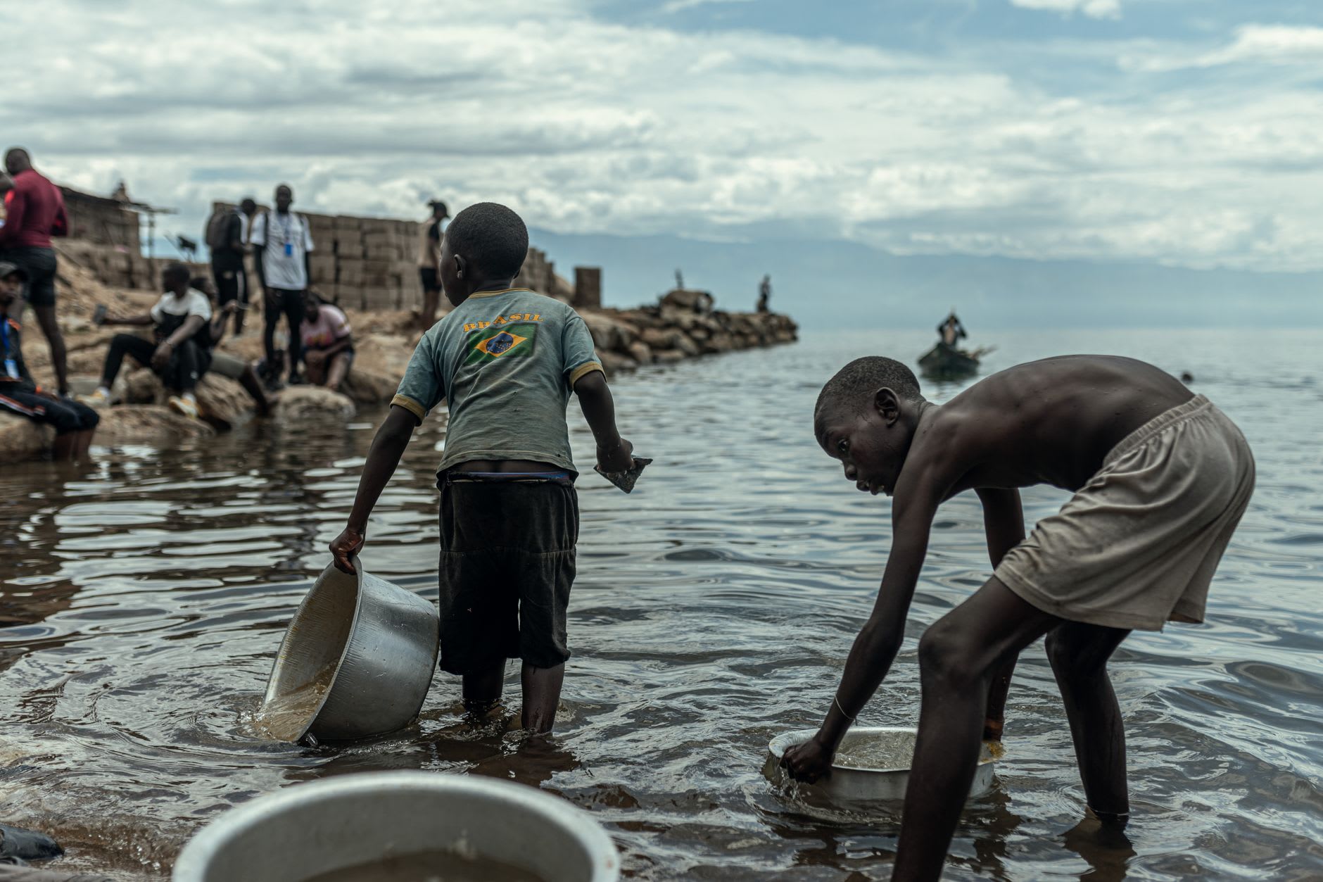 Wooden fishing pirogues pulled up on the rocky shore of Lake Kivu at sunset
