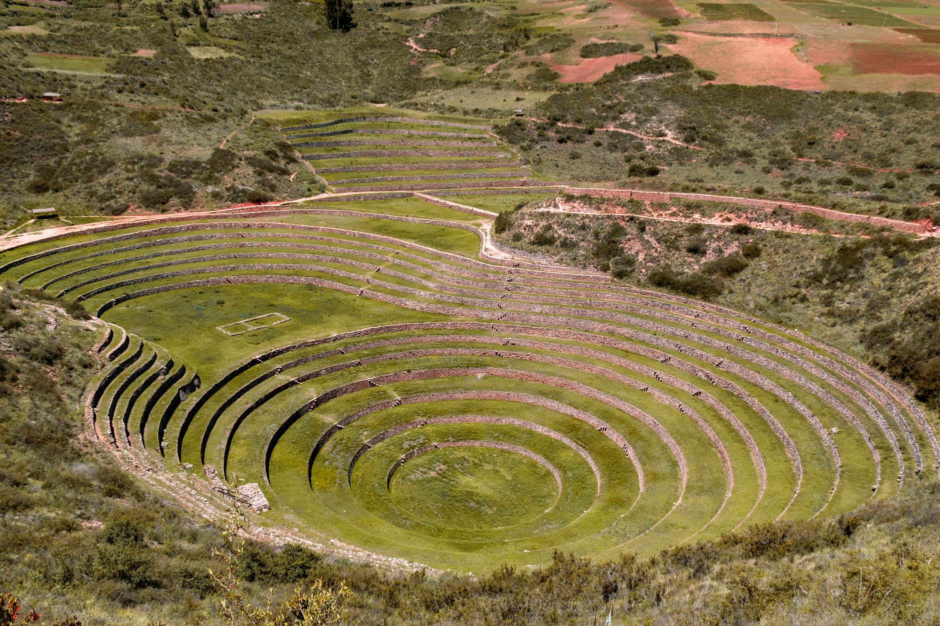 The long stone-and-adobe kallanka hall of Huchuy Qosqo with trapezoidal doorways, the Sacred Valley spread out far below