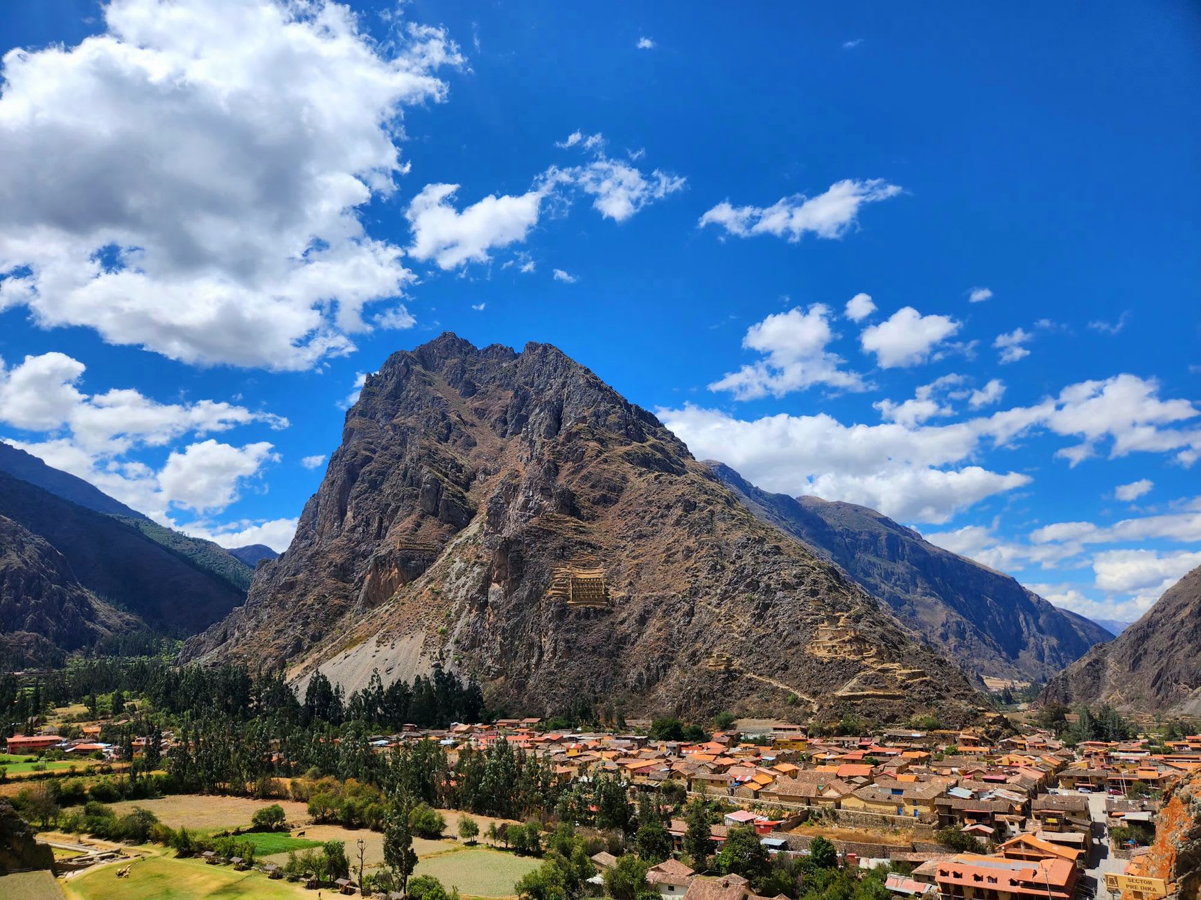 Ollantaytambo's original Inca street grid, stone water channels running between the walls, the fortress visible above