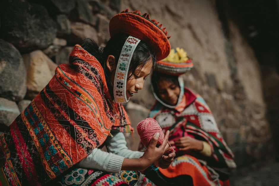 Weaver's hands guiding thread on a traditional backstrap loom in Patacancha