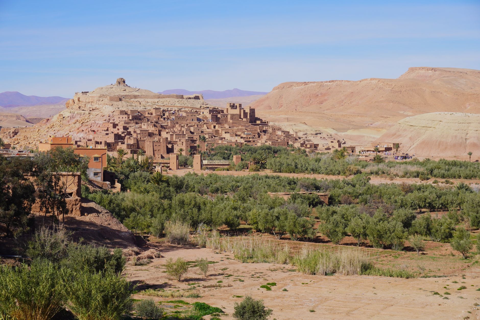 Ksar Aït Benhaddou on its hillside, warm amber pisé walls rising above the Ouarzazate river valley