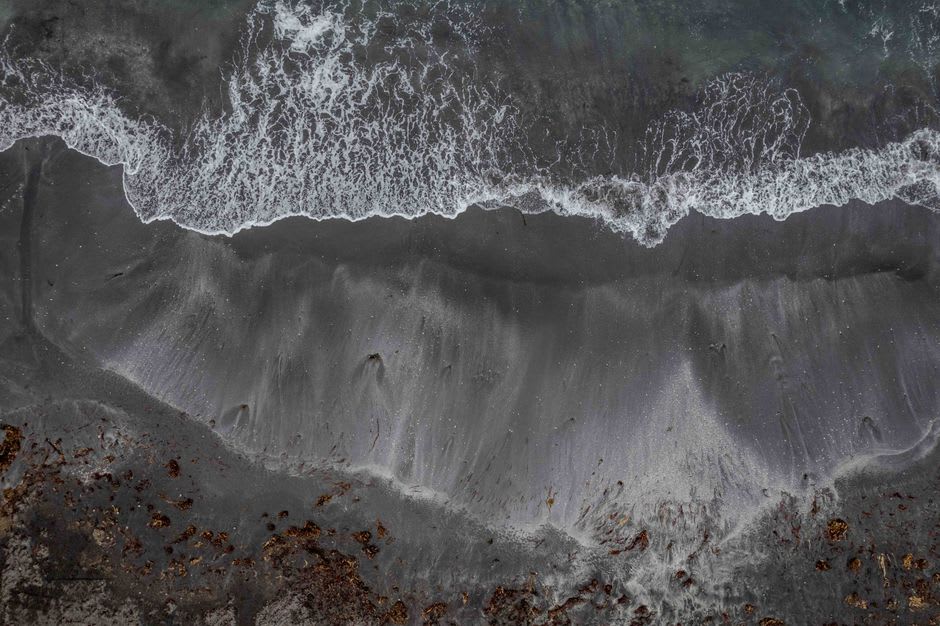 Una vista cercana de la arena volcánica oscura y el oleaje atlántico más fuerte rompiendo en Conaree Beach