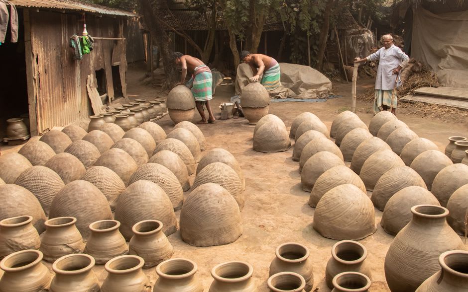 Rows of hand-built clay pots drying in the sun outside a pottery workshop in Newcastle Village