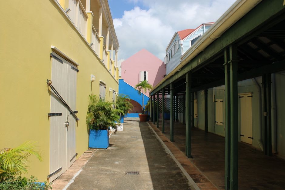 A narrow street in Sandy Point Town lined with pastel-colored wooden houses and a view of the sea at the end