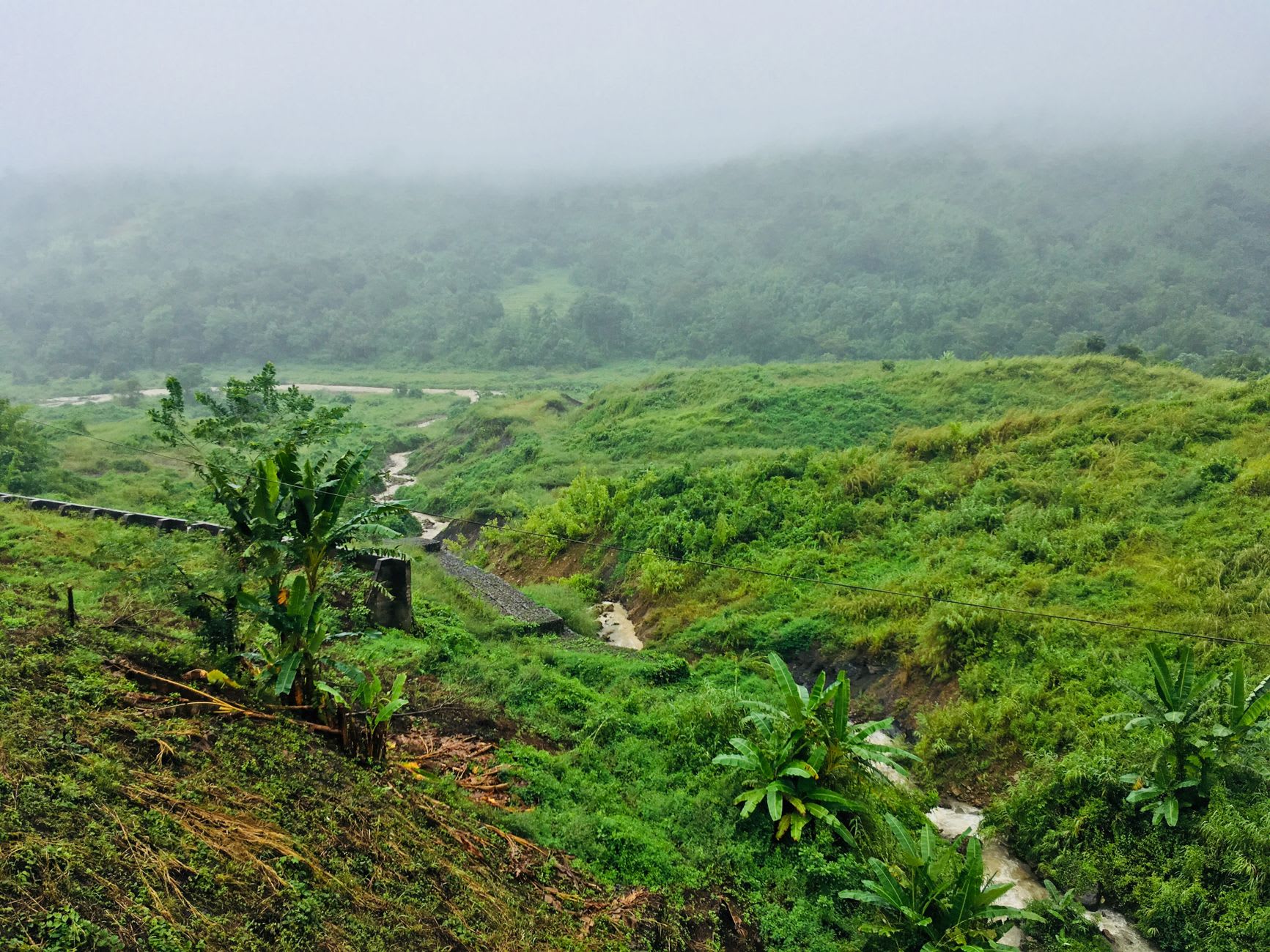 Steam rising from active fumaroles at Sulphur Springs, the mineral-stained landscape in yellow and grey with Soufrière visible in the valley below
