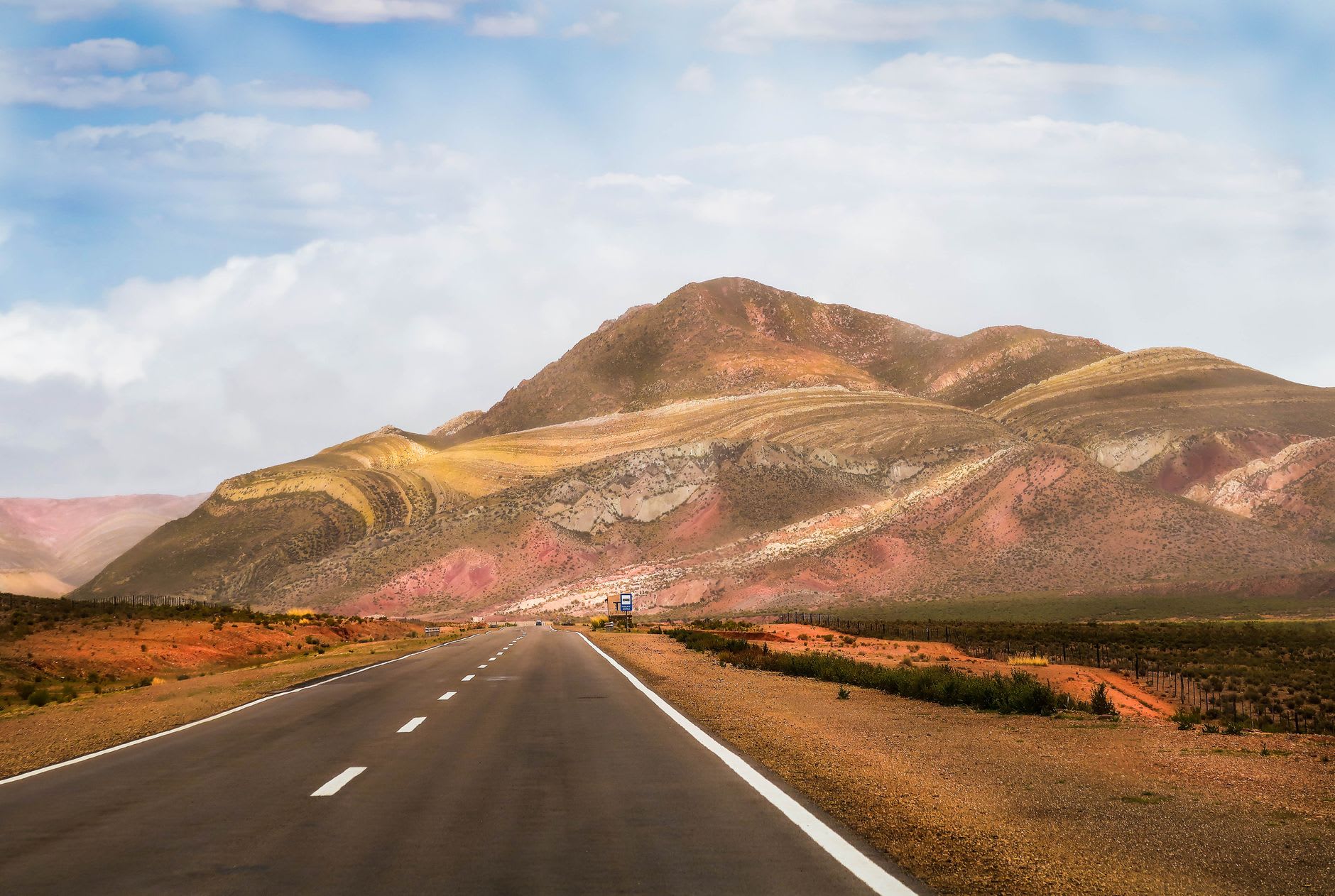 A dusty stretch of unpaved Ruta 40 winding between dry red mountains toward the village of Molinos, Calchaquí Valleys Argentina