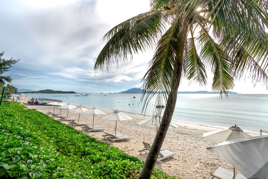 The white sand curve of Lefaga's Return to Paradise beach with palms framing the bay