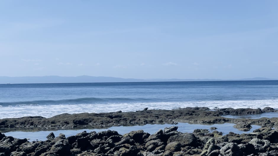 Beach fales along the shore at Manase at low tide with the reef visible offshore