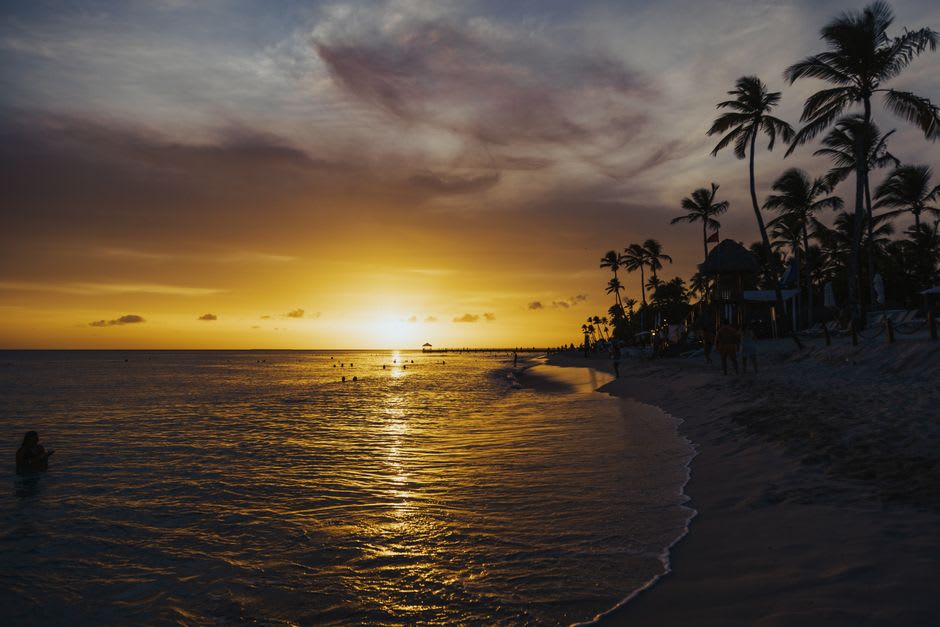 Sunset over the water at Manase, the sky turning orange behind silhouetted palm trees