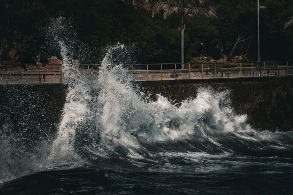 Waves breaking against the seawall at the tip of the Mulinuu Peninsula, Apia's harbor beyond
