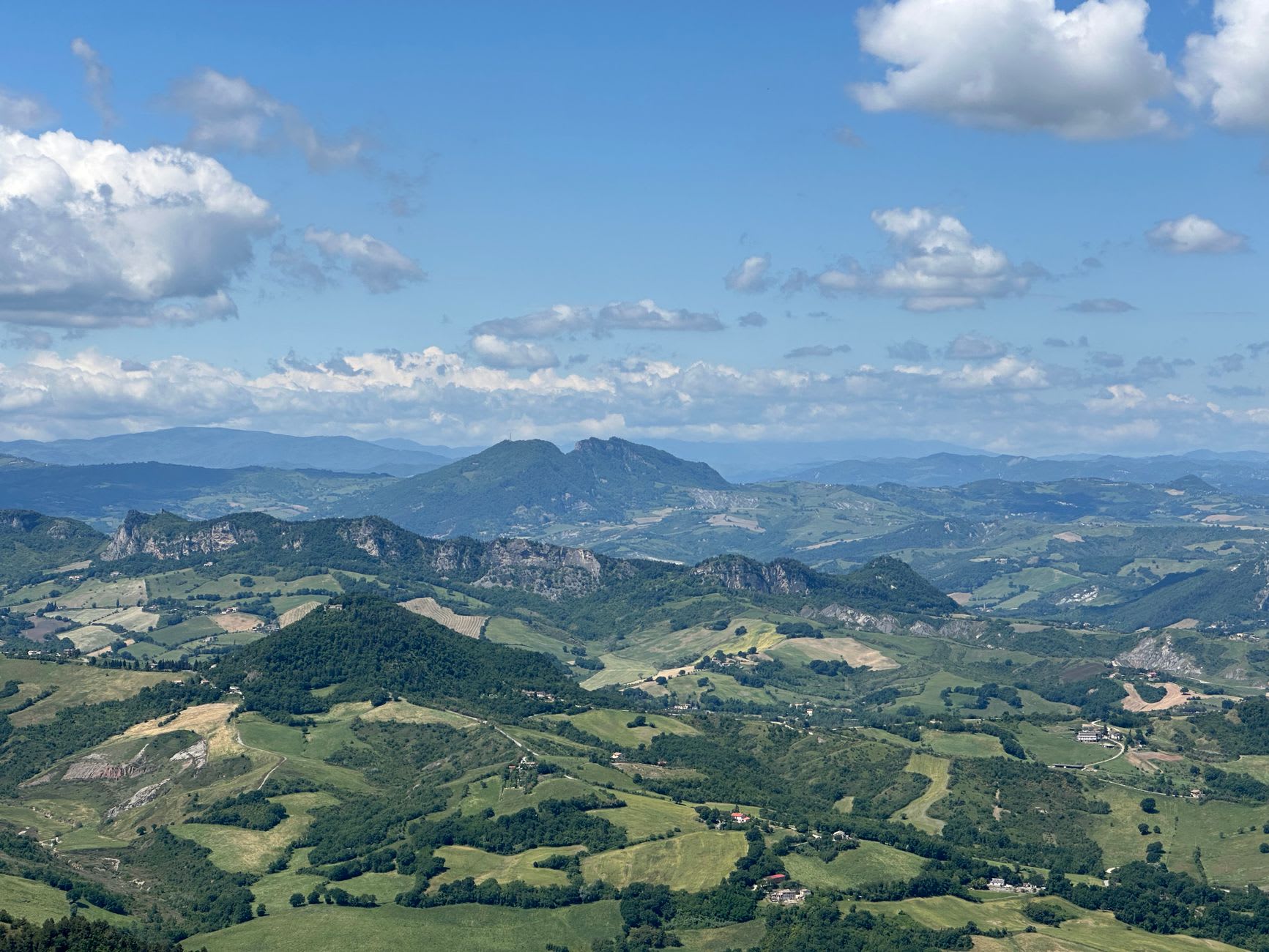 The Passo delle Streghe path curving along the limestone cliff face, the low outer wall to the left and the vertiginous drop to the Romagna plain visible below