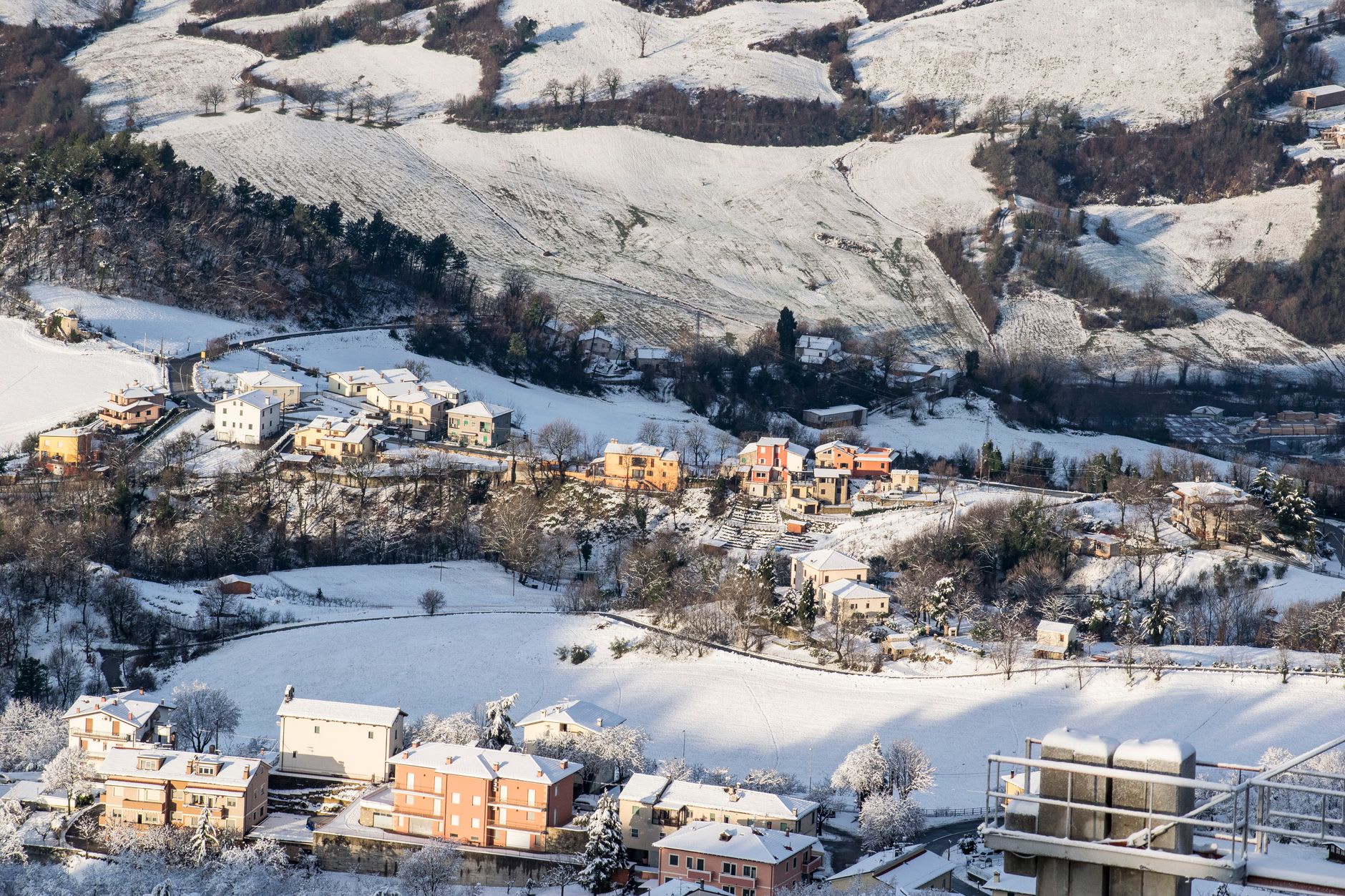 La rue commerçante principale de Serravalle avec ses boutiques et cafés au service des habitants, les tours du Monte Titano à peine visibles sur l'horizon méridional