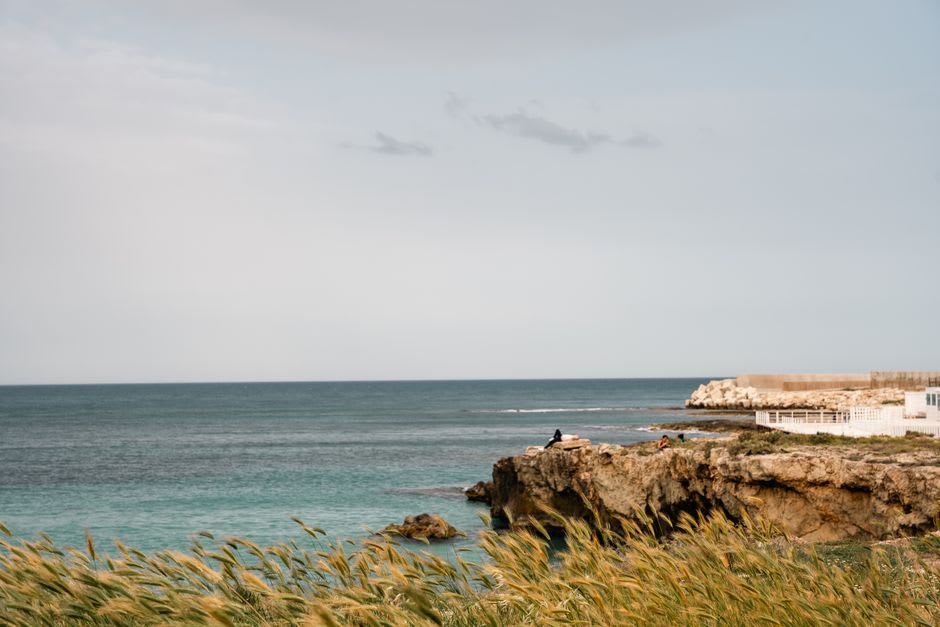 Local teenagers cliff-jumping into clear water at Cala Ginepro near Budoni