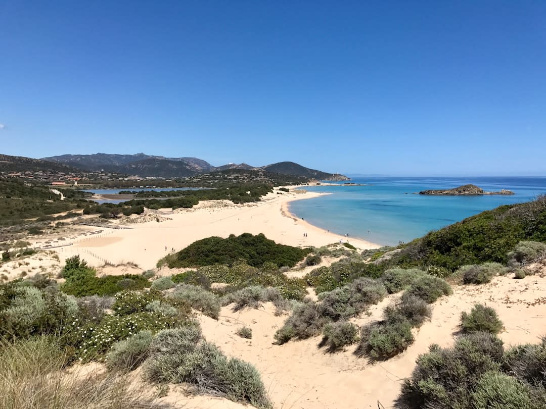 La torre de vigilancia Torre di Chia sobre la curva de dunas de la playa de Su Giudeu a la hora dorada