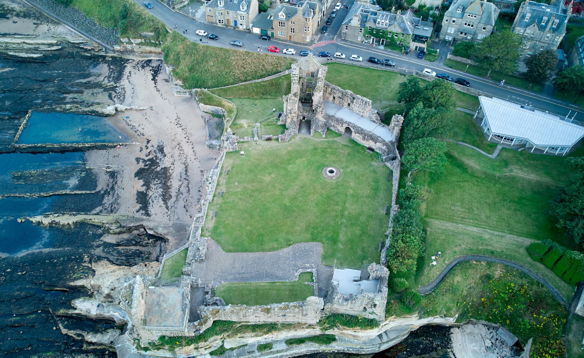 St Andrews Cathedral ruins from the inside of the nave, roofless and open to a white sky, ancient headstones filling the floor