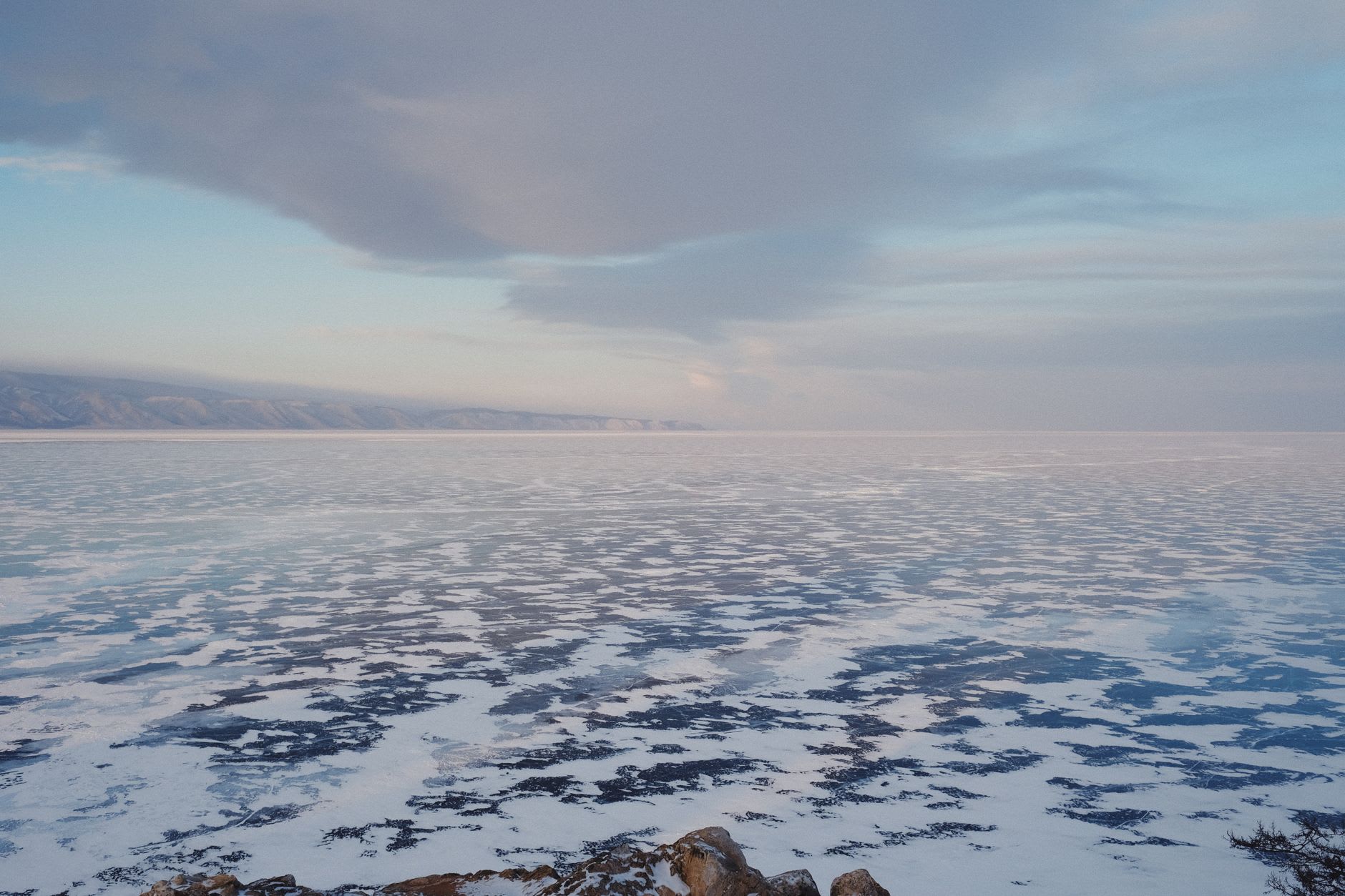 Translucent green Baikal ice with deep fissures and bubbles frozen mid-rise, caught in winter afternoon light