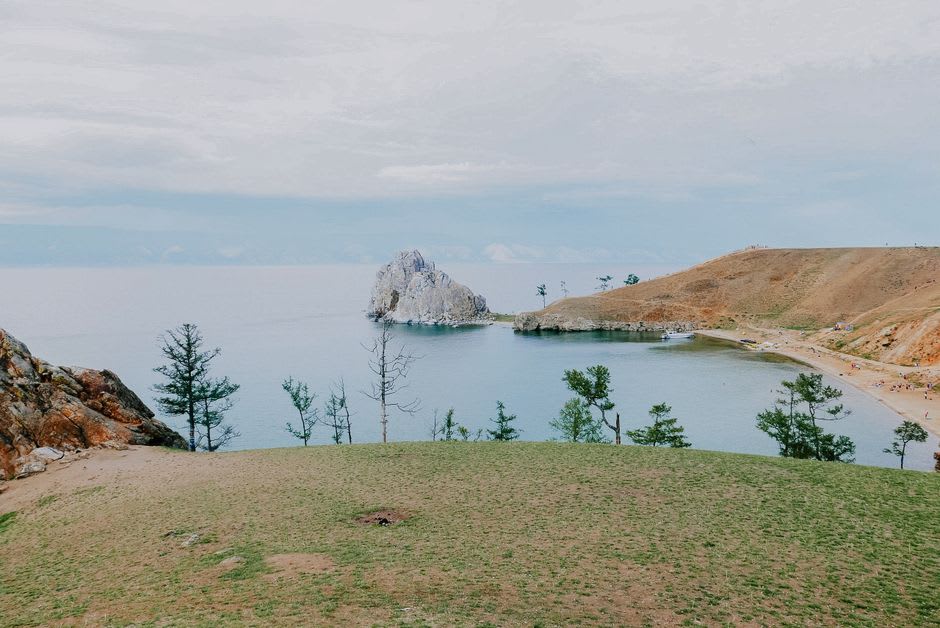 A weathered fishing boat pulled up on Olkhon's shoreline with steppe hills in the background