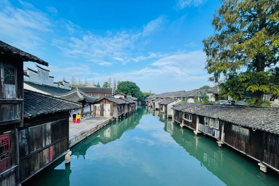 A narrow canal lined with old wooden shopfronts in Dujiangyan's preserved old town