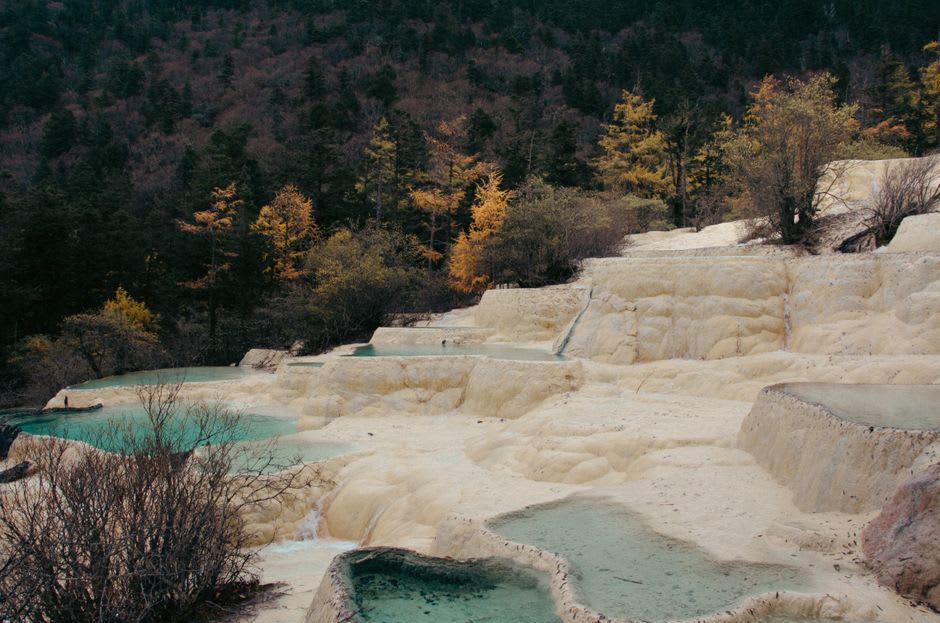 Terraced travertine pools in shades of gold and turquoise along the Huanglong boardwalk
