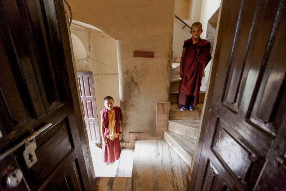 Young monks in maroon robes walking through the courtyard at Rumtek Monastery