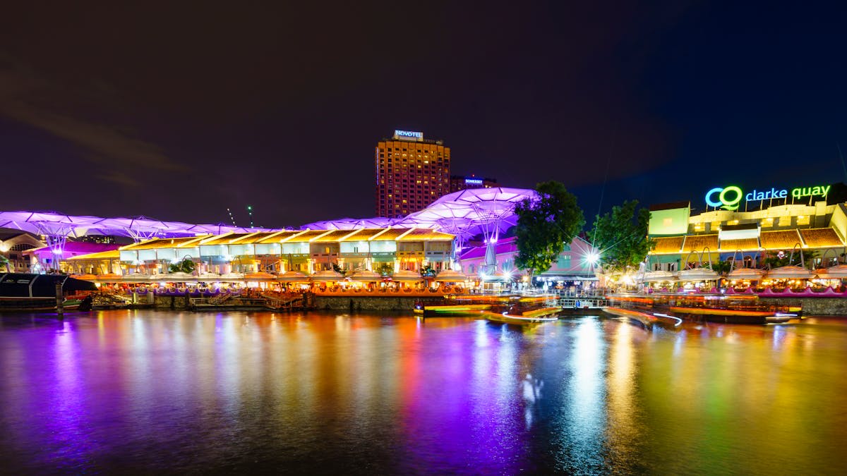 The colourful illuminated buildings of Clarke Quay reflected in the Singapore River at night