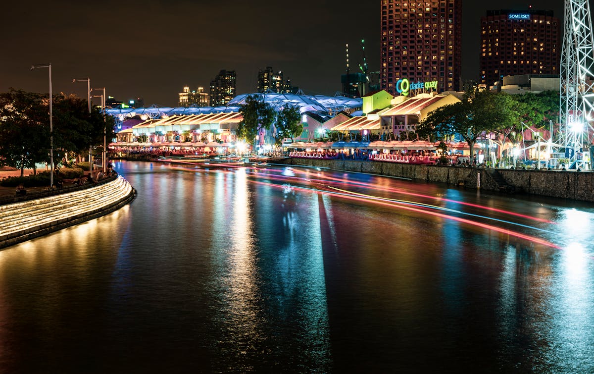 The Singapore River flowing past the restored warehouse buildings of Clarke Quay at dusk